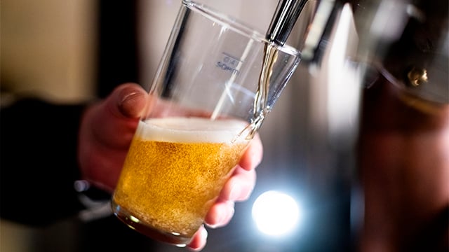 Bartender pouring crafted beer from tap in glass