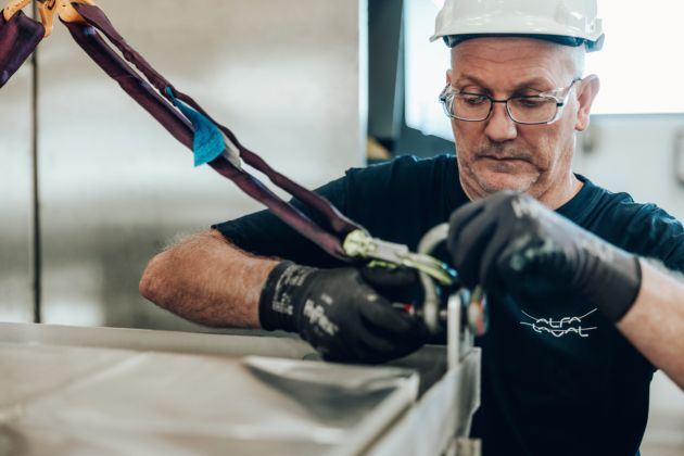 Close up of a worker installing membrane filtration equipment using safety gear and lifting straps